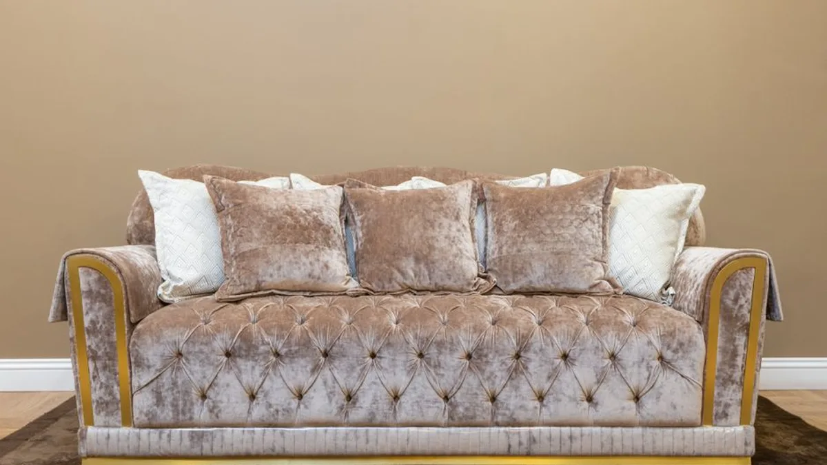 Canapé beige à trois places en tissu dans un salon lumineux avec coussins contrastés