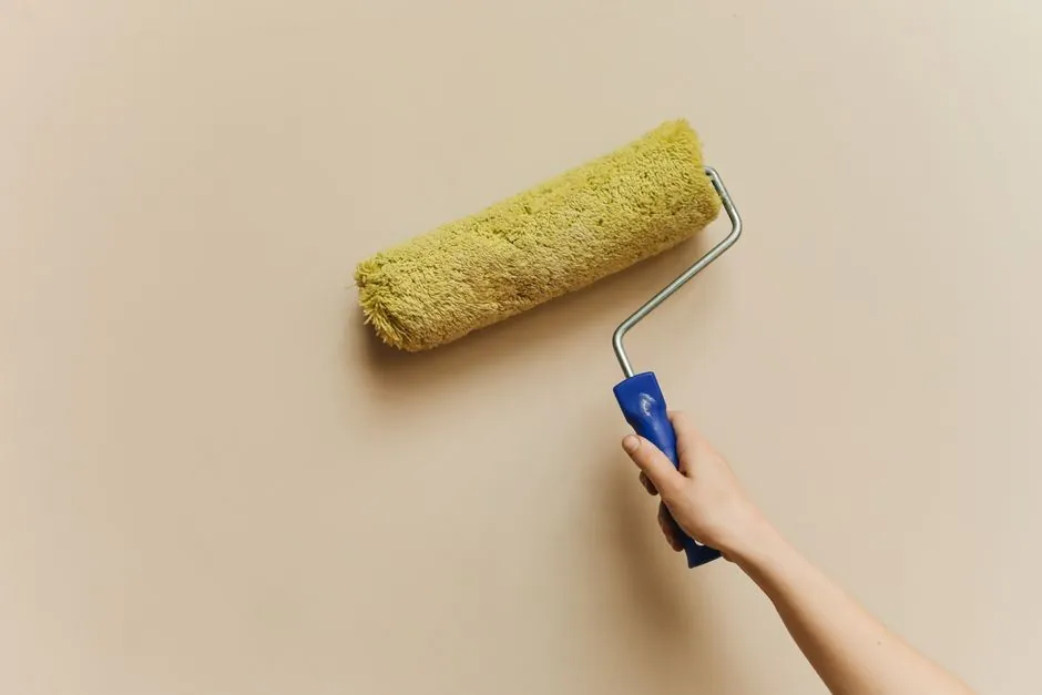 Rouleau de peinture appliqué sur un mur beige